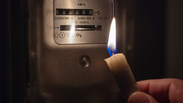 The electricity meter is illuminated by the light of a candle. Power outage, blackout concept.