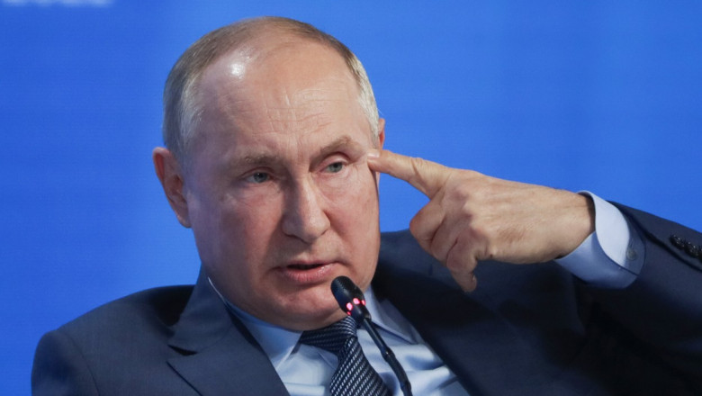 Vladimir Putin, cu degetul la cap, la o conferință de presă.