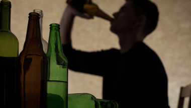 profil in penumbra al unui barbat care bea dintr-o sticlă