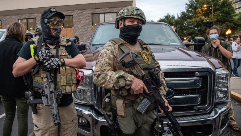 bărbați înarmați și acoperiți de armură militară în fața unei mașini