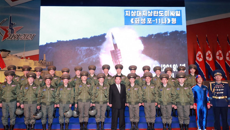 Kim Jong-un pozează cu mai mulți militari în fața unui ecran în care e redată testarea unei rachete balistice