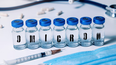doze de vaccin inscripționate cu litere care formează cuvântul omicron și o seringă lângă