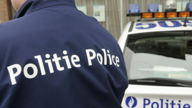 Polițist belgian pe stradă, lângă mașină.