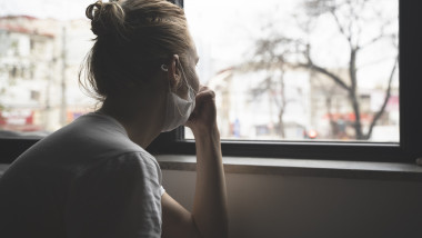 woman with protection medical face mask by the window