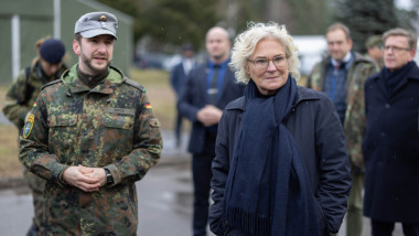 Christine Lambrecht cu pardesiu si ochelari, alaturi de un soldat german in camuflaj