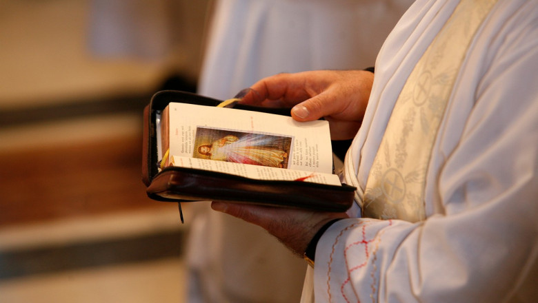 mainile unui preot catolic cu o carte de rugaciuni