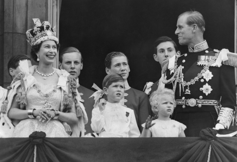 Queen Elizabeth II gestures as her husband Duke of Edinburgh Prince Phillip and children Prince Charles and Princess Anne watch the Royal Air Force flypast salute from the balcony of Buckingham Palace 2 Junne 1953