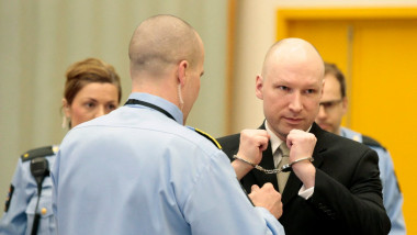 Anders Breivik cu cătușele la mâini stă în fața unui polițist
