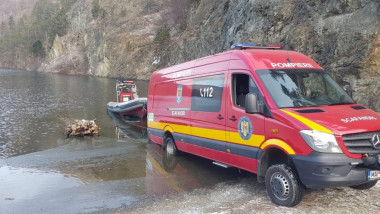 O mașină a pompierilor descarcă o barcă pe suprafața unui lac
