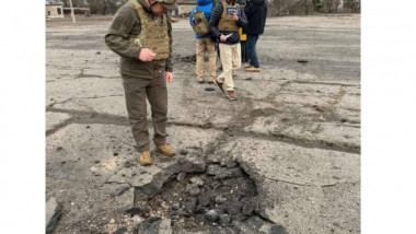 un soldat inspectează un crater produs de o lovitură de mortier în estul Ucrainei