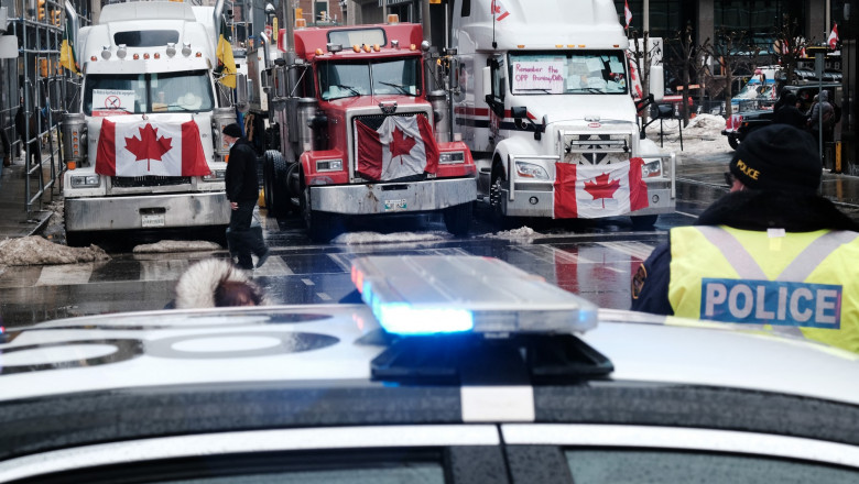 Camioane cu steagul Canadei și o mașină de poliție