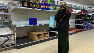 A shopper looks at empty shelves at a supermarket in London