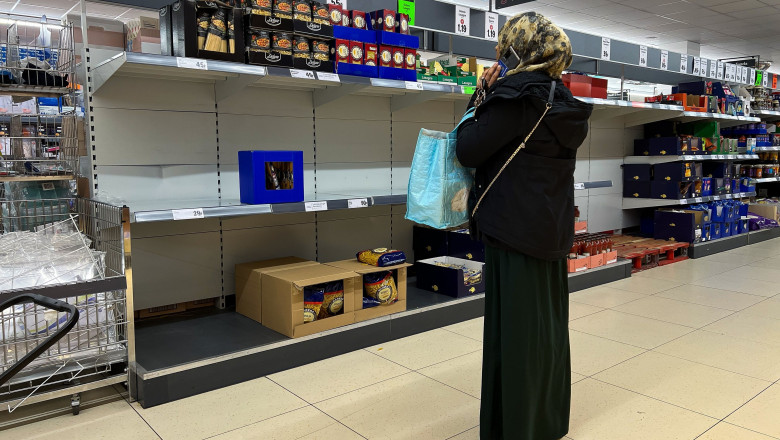 A shopper looks at empty shelves at a supermarket in London