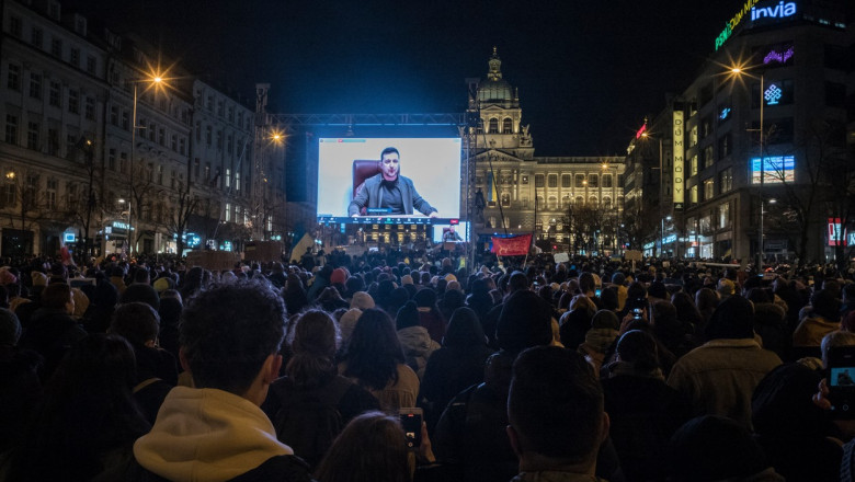 oameni adunați în Praga îl ascultă pe Volodimir Zelenski de pe un ecran uriaș