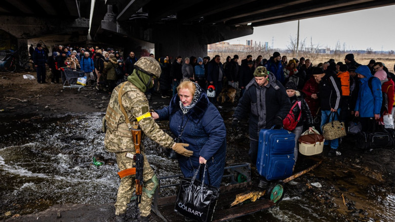 Un militar ucrainean îi ajută pe civilii care încearcă să fugă din calea invaziei rusești.