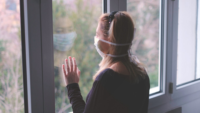 femeie cu masca, priveste pe geam