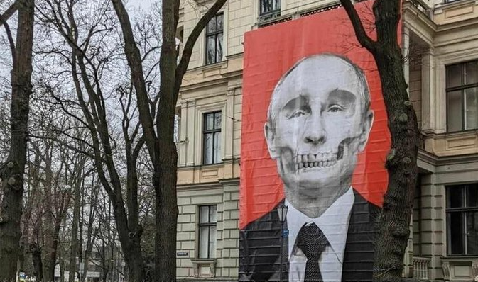 Un poster cu portretul lui Putin sub formă de craniu, expus pe faţada unui muzeu din Riga, aflat vizavi de ambasada Rusiei
