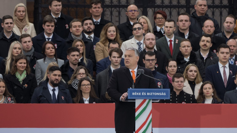 Viktor Orban la pupitru cu un grup de oameni într-o gradenă în spatele lui