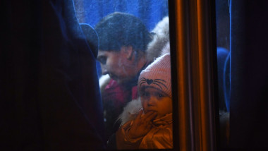 O femeie și un copil de la geamul unui autocar