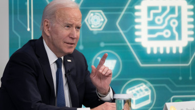 Joe Biden vorbește în fața unui panou cu simboluri digitale