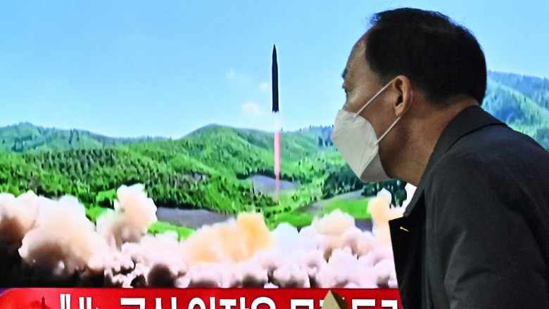 A man walks past a television report showing a news broadcast with file footage of a North Korean missile test