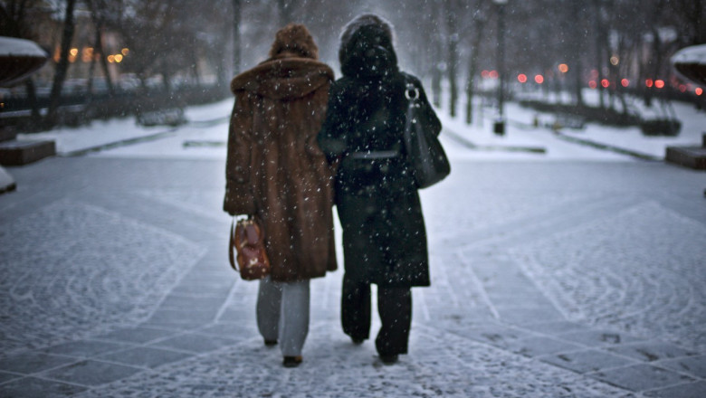 femei pe strada in ninsoare la moscova vazute din spate cu haine de blana