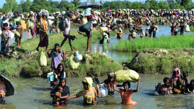 Refugiați rohingya traversează un râu pentru a scăpa de violențele din Myanmar