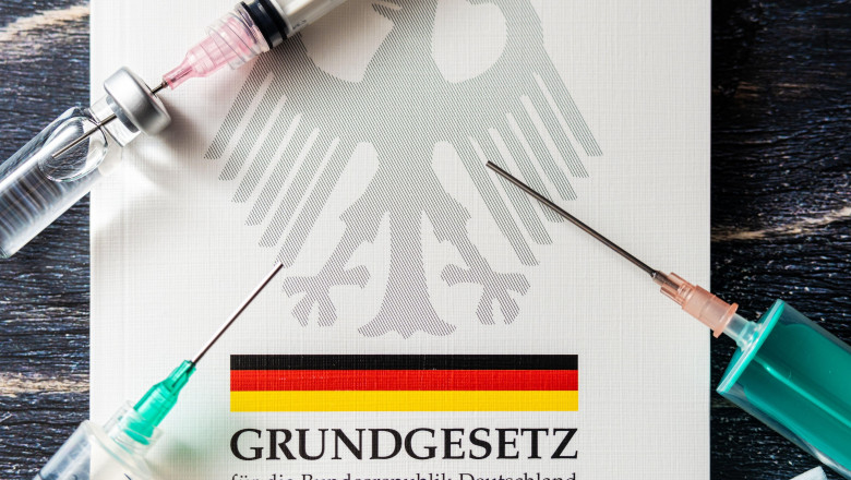 The German Basic Law Book With Syringes As A Version With The Duty To Vaccinate, Anchoring The Duty To Vaccinate In German Law - PHOTOMONTAGE
