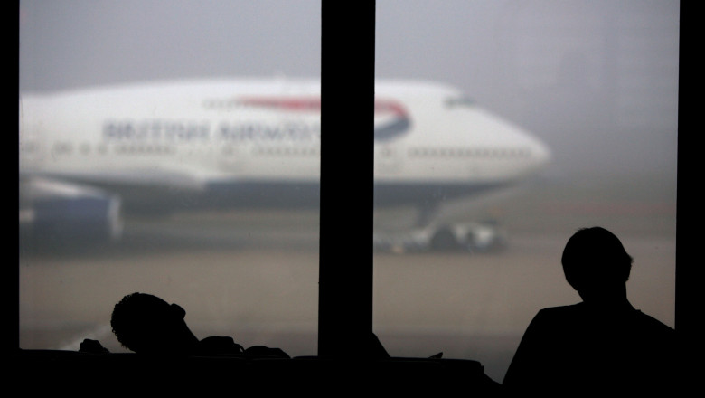 Sleeping British Airways passengers at London Heathrow wait for flights delayed by fog