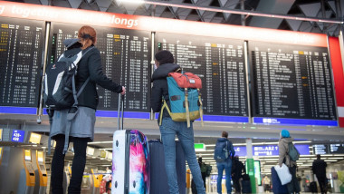 pasageri se uita la tabloul plecarilor pe aeroportul din frankfurt