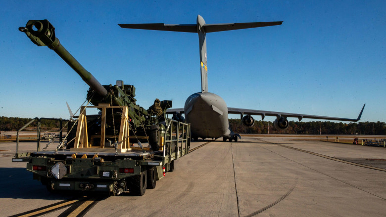 U.S. Marines with Combat Logistics Company 21 and U.S. Airmen with the 16th Airlift Squadron guide an M777 towed 155mm howitzer into a U.S. Air Force C-17 Globemaster III at Marine Corps Air Station Cherry Point, North Carolina, Nov. 30, 2021. The Marines