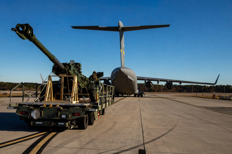 U.S. Marines with Combat Logistics Company 21 and U.S. Airmen with the 16th Airlift Squadron guide an M777 towed 155mm howitzer into a U.S. Air Force C-17 Globemaster III at Marine Corps Air Station Cherry Point, North Carolina, Nov. 30, 2021. The Marines