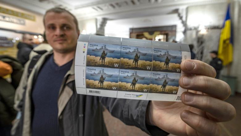 A local resident shows new Ukrainian stamps titled "Russian warship, Go...!" at a post office in the center of Kyiv