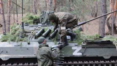 Doi militari ruși încarcă muniție într-un blindat.