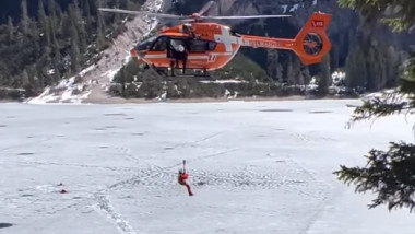 Un elicopter scoate oameni cazuți într-un lac înghețat.