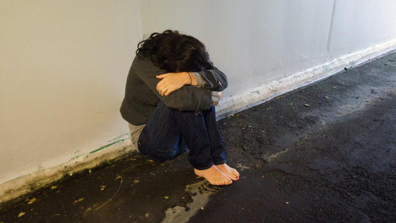 femeie care sta pe jos cu capul pe genunchi si ffata ascunsa, victima abuz