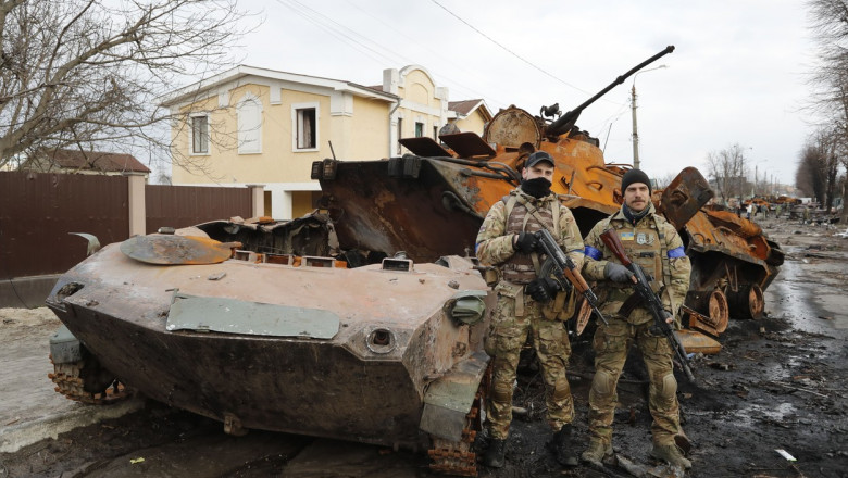 Militari Ucrainei lângă un blindat rusesc distrus.