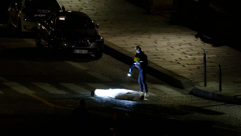 A police officer investigates the body of one of two people shot by police in Paris on April 25, 2022.