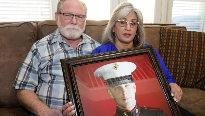 Joey and Paula Reed pose for a photo with a portrait of their son Marine veteran and Russian prisoner Trevor Reed at their home in Fort Worth, Texas