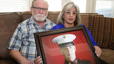 Joey and Paula Reed pose for a photo with a portrait of their son Marine veteran and Russian prisoner Trevor Reed at their home in Fort Worth, Texas
