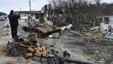 O persoană face poze la epava unui tanc rusesc distrus în apropiere de Kiev