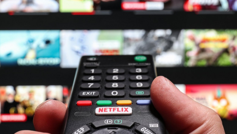 Un bărbat ține în mână o telecomandă pentru Netflix.