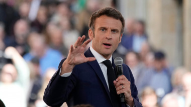 Președintele francez Emmanuel Macron. gesticuleaza cu microfonul in mana cealalta