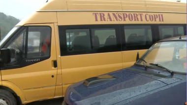 microbuz scolar cu inscriptia transport copii langa o masina neagra