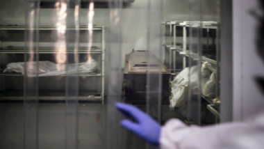 Imagine de la morga unui spital, cu decedați și un sicriu.
