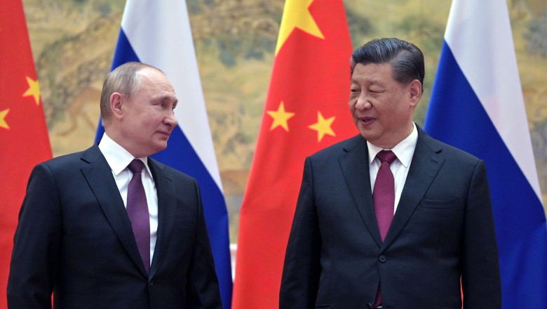 Vladimir Putin și Xi Jinping se uita unul spre altul cu steagurile in spate