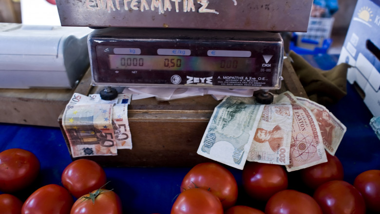 euro notes L and defunct drachma notes are displayed on a tomato stal