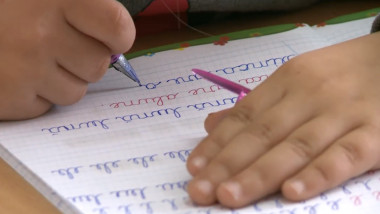 copil scrie caiet maini
