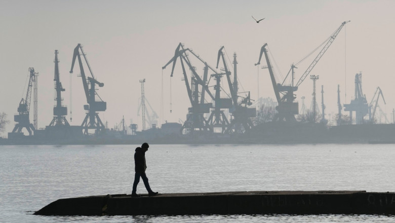 FILE - A man walks in front of harbor cranes at the port in Mariupol, Ukraine, Wednesday, Feb. 23, 2022