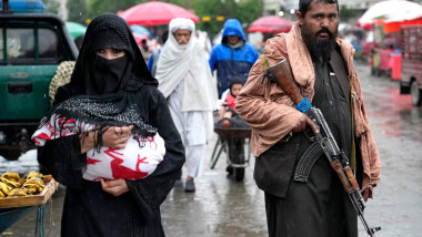 femei cu burka în afghanistan și un bărbat înarmat cu o pușcă AK-47